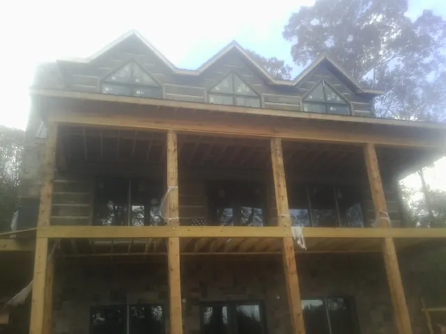 Dormers and porch framing on a large log home under construction — Roof Coating work by our crew in Saint James